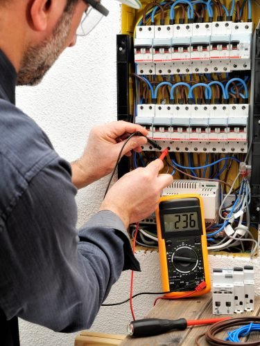 Technical electrician measures the voltage of a circuit breaker of a residential electrical panel
