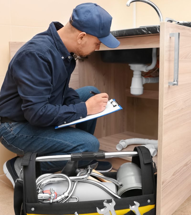 Plumber with set of tools and clipboard in kitchen